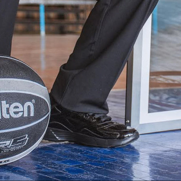 Person holding a Molten basketball on a basketball court with a hoop in the background.